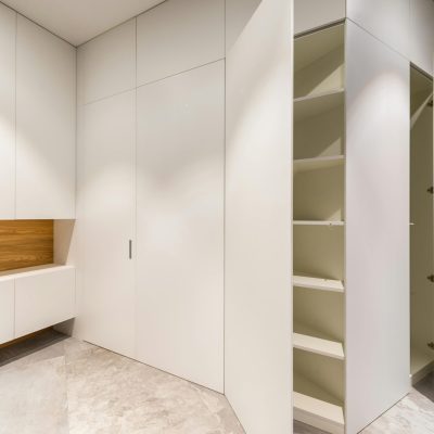 Contemporary empty room with white closet and shelves above gray floor in light house